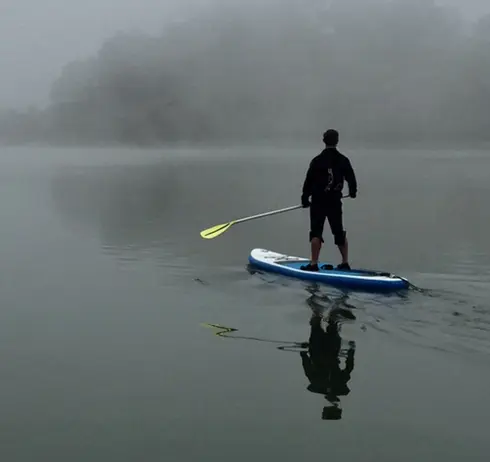 Man paddleboarding through a thick fog