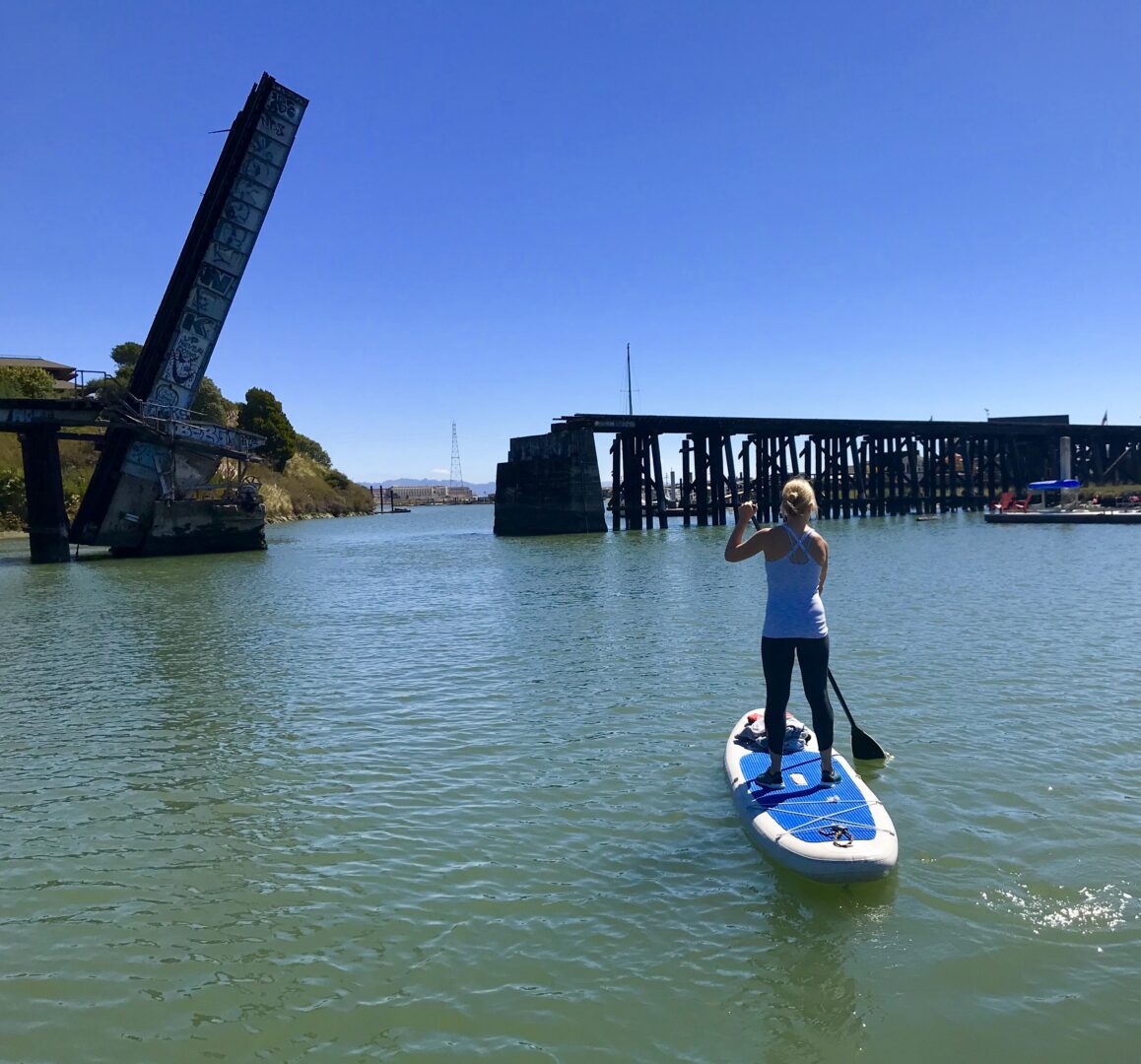 Woman paddleboarding near an old bridge