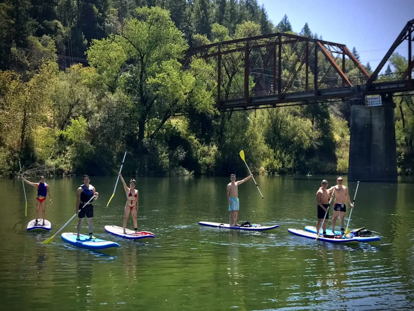 Group of six paddleboarding near a bridge